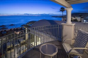 Ein Balkon mit Meerblick, Sitzgelegenheiten im Freien und einer Palme.