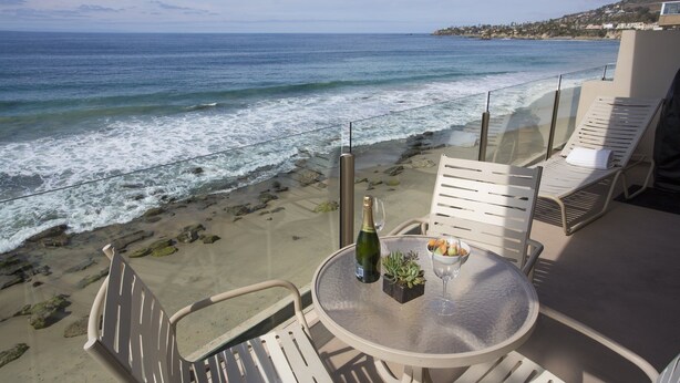 Een balkon met een tafel, stoelen en uitzicht op de oceaan.