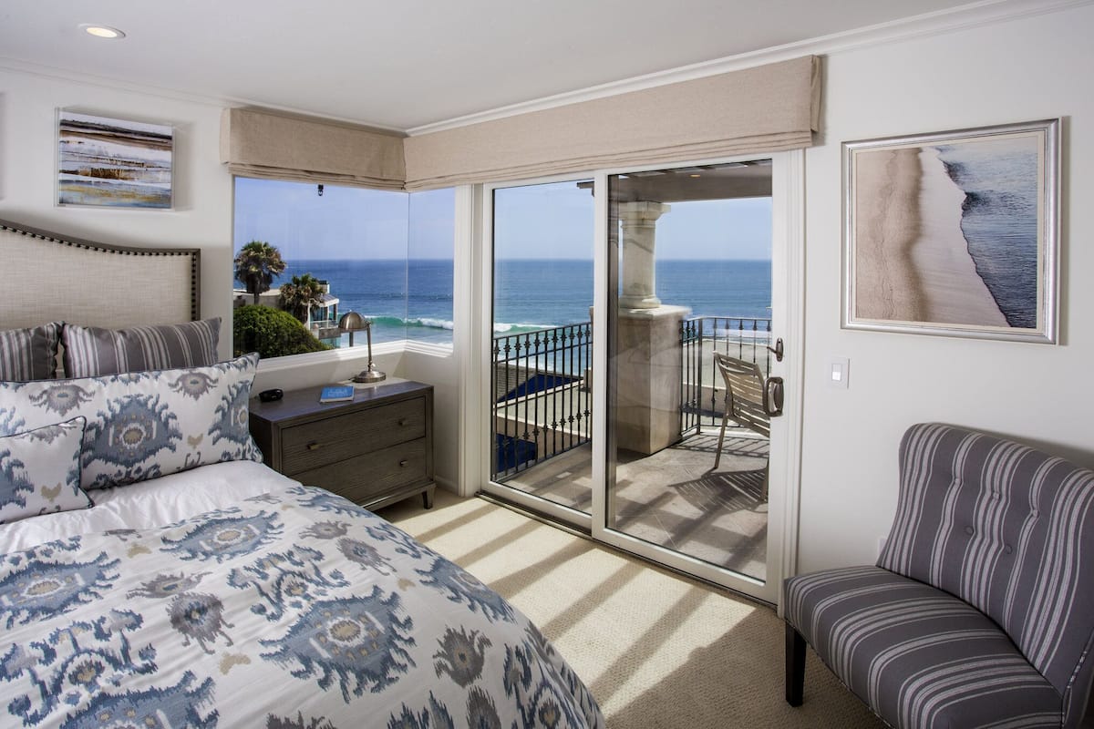 Une chambre avec un lit, une table de chevet, une chaise et un balcon donnant sur l’océan.