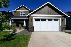 A two-story house with a garage, a front porch, and a well-maintained lawn.