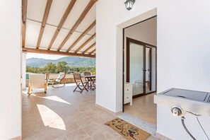 A patio area with a table and chairs, a doggy door mat, and a view of mountains. - Casa Luna sea view and private parking (TERTENIA)
