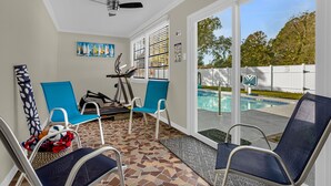 A sunroom with a view of a swimming pool, exercise equipment, and several chairs. - Home Paradise Lakeland Heated Pool • Jacuzzi • BBQ Backyard (Lakeland)