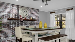 A dining area with a brick wall, a clock, and a table with chairs. - Home Paradise Lakeland Heated Pool • Jacuzzi • BBQ Backyard (Lakeland)