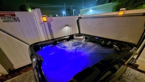 A hot tub with a blue light, surrounded by a white fence and a sign indicating a restricted area. - Home Paradise Lakeland Heated Pool • Jacuzzi • BBQ Backyard (Lakeland)