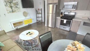 Una cocina moderna con electrodomésticos de acero inoxidable, un comedor con una mesa redonda y sillas, y una sala de estar con un sofá y una mesa de centro.