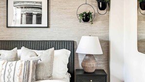 A bedroom with a bed, bedside table, lamp, and wall-mounted plants. - Lincoln Lofts: 202 | Bright & Stylish DC Retreat (Washington)