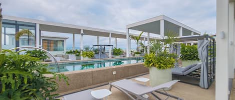 Un espace piscine aménagé sur le toit, avec des chaises longues, des jardinières et une vue sur la ville.