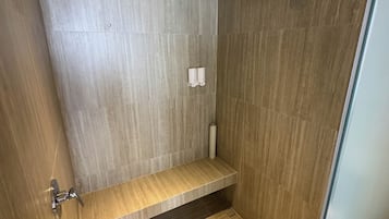 Eine moderne Dusche mit Holzwänden und einer eingebauten Ablage.