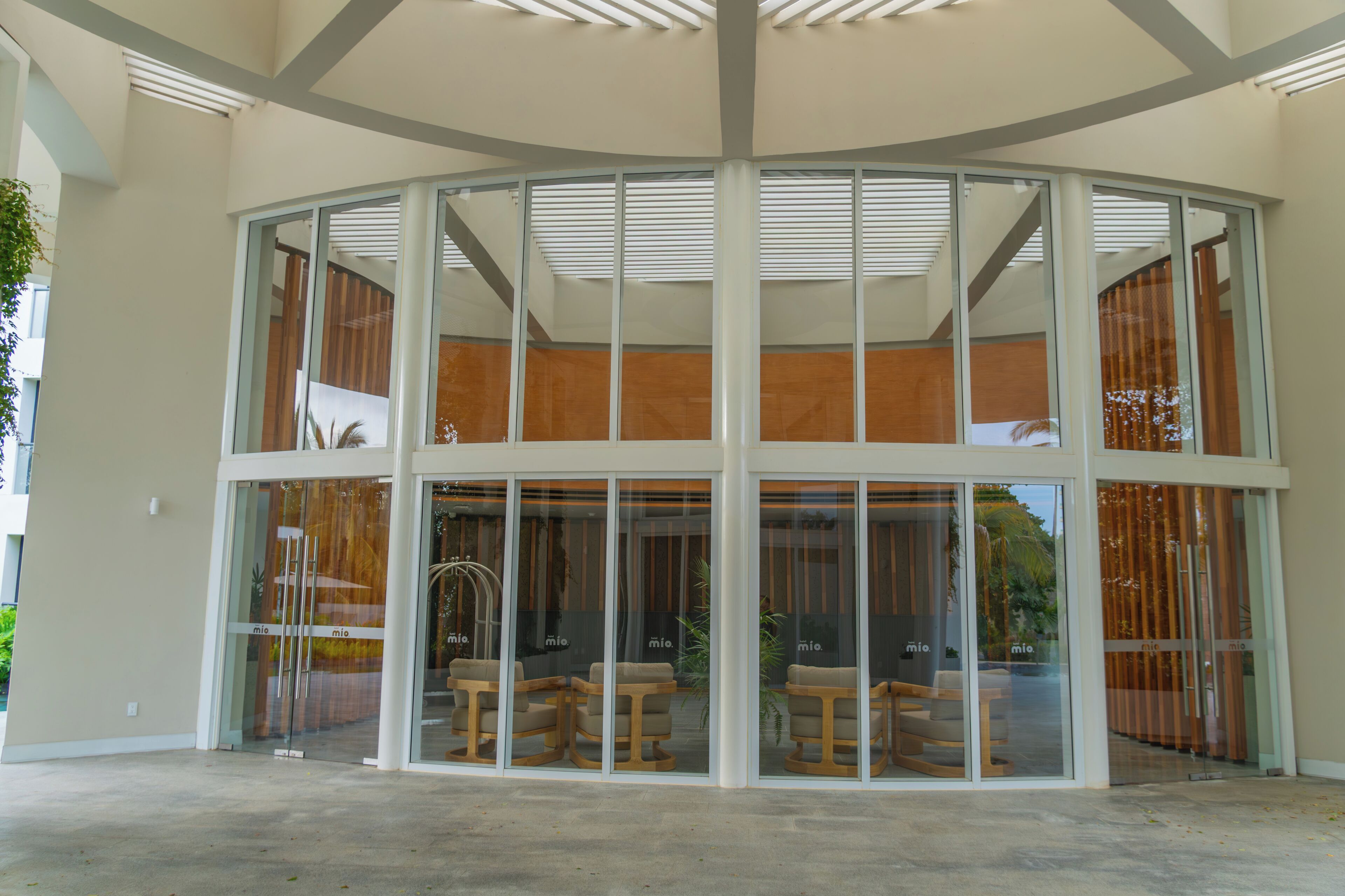A modern building with a glass facade, wooden interior seating, and a central column structure.