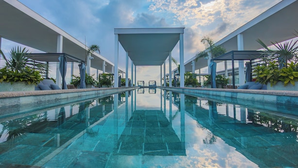 A modern pool area with clear water, surrounded by white columns and covered seating areas. - Hotel Mio Riviera Nayarit - Adults Only (Nuevo Nayarit)