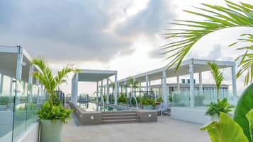 Een zwembad op het dak met glazen balustrades, palmbomen en een modern architectonisch ontwerp.