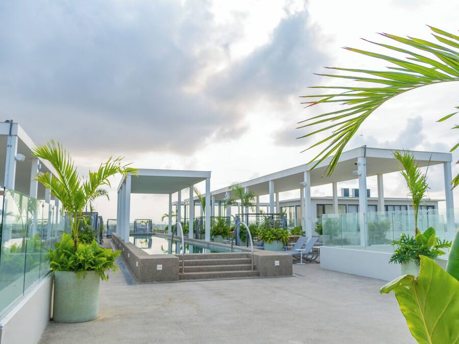 Een zwembad op het dak met glazen balustrades, palmbomen en een modern architectonisch ontwerp.
