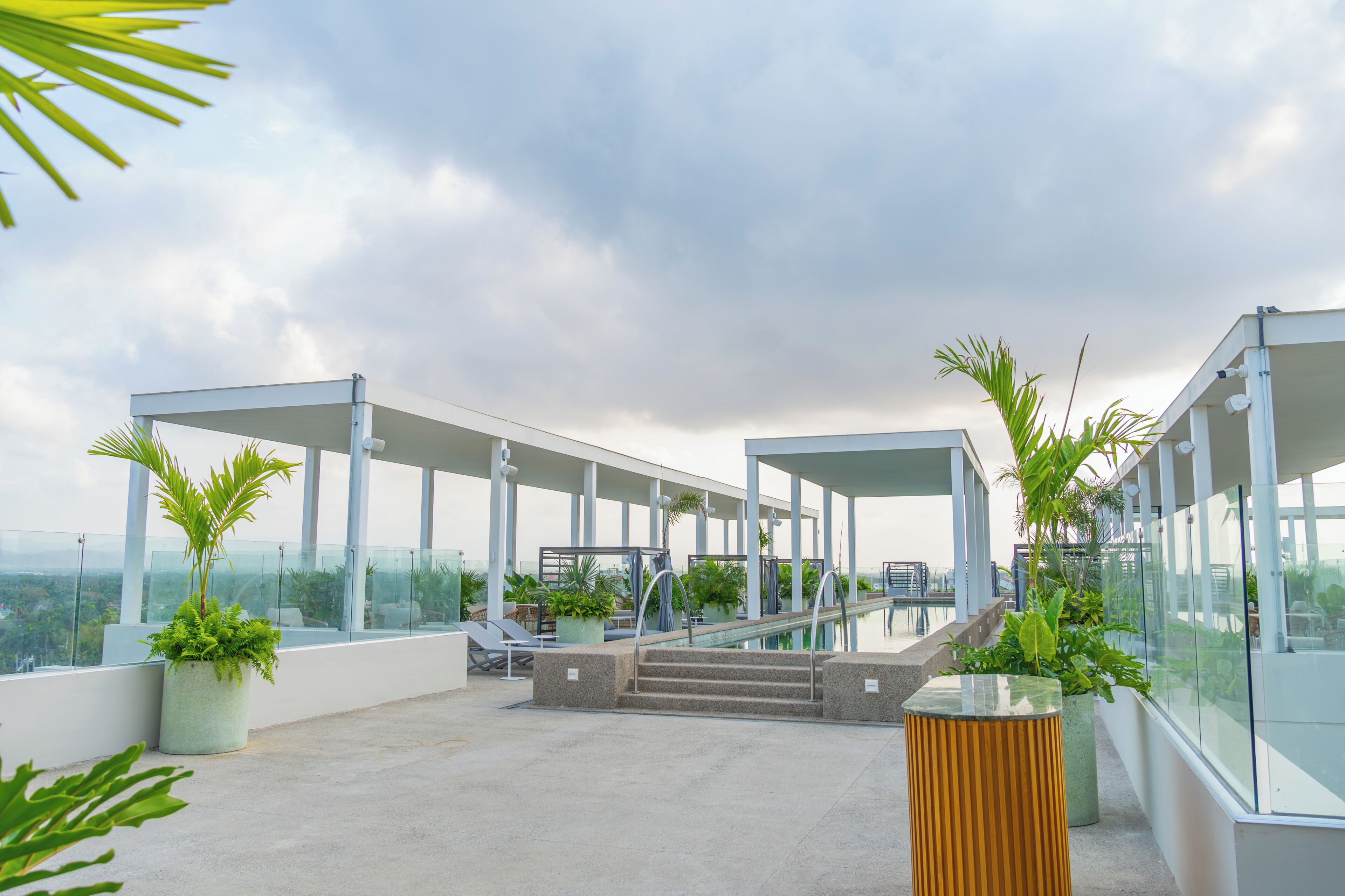 A rooftop terrace with glass railings, outdoor seating, and potted plants.