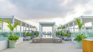 Un espace piscine aménagé sur le toit, avec des chaises longues et des plantes en pot.