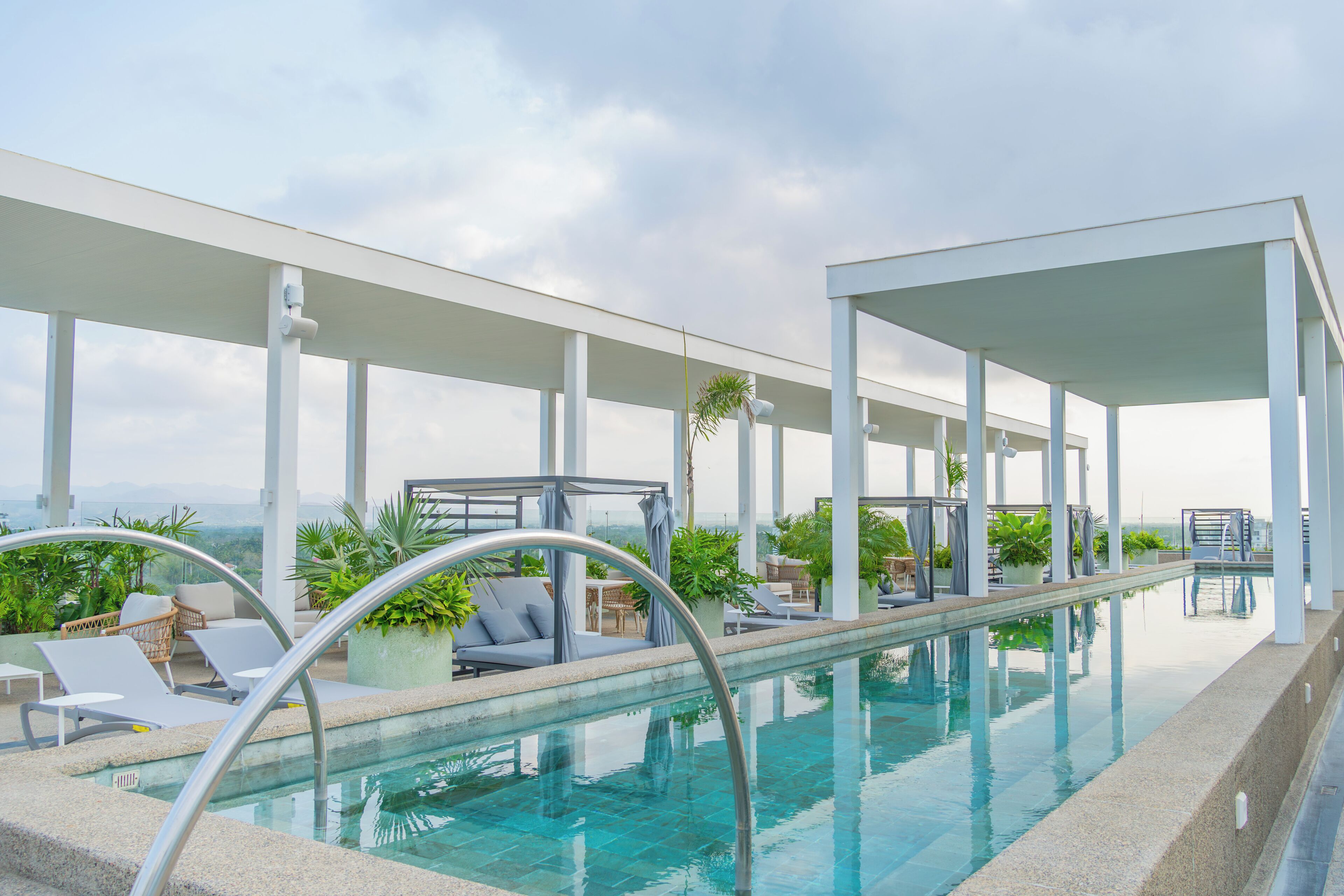 A rooftop infinity pool with lounge chairs and potted plants.