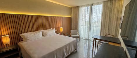 Ein Hotelzimmer mit einem großen Bett, Nachttischen, einem Schreibtisch und einem Stuhl.