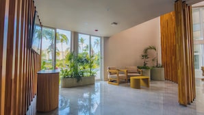 A modern lobby with a polished floor, wooden paneling, and a seating area with two chairs and a small table. - Hotel Mio Riviera Nayarit - Adults Only (Nuevo Nayarit)
