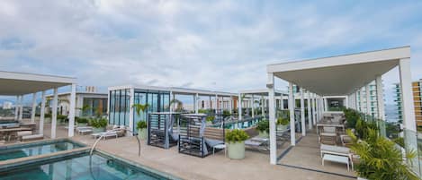 A rooftop pool area with lounge chairs and a glass-enclosed cabana.