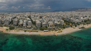 An aerial view of a coastal city with dense urban development, a beach, and clear turquoise waters.