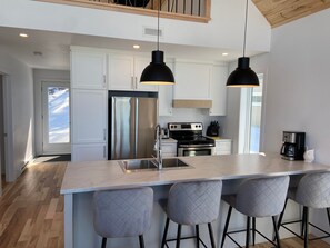Una cocina moderna con una isla central, electrodomésticos de acero inoxidable e iluminación colgante.