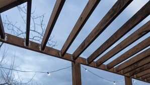 Un jacuzzi bajo una pérgola de madera con vistas a árboles y montañas.