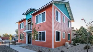 A multi-story residential building with a red exterior, a balcony on the second floor, and a sloped roof. - One Bedroom Hideaway (Reno)