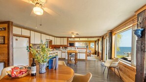 A spacious kitchen with wooden cabinets, a dining area with a wooden table and chairs, and large windows offering a view of the sea. - Lakeview Retreat near Green Bay, Door County (Kewaunee)
