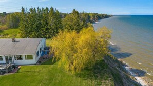 A coastal house with a large deck, surrounded by trees and a view of the ocean. - Lakeview Retreat near Green Bay, Door County (Kewaunee)