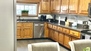 Una cocina con armarios de madera, lavavajillas, cafetera y licuadora.