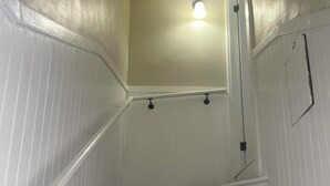 Un escalier aux murs blancs, avec un luminaire au sommet.