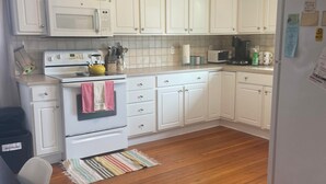 Une cuisine avec des meubles blancs, un four à micro-ondes, une cuisinière et un réfrigérateur.