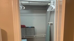 Une pièce de taille modeste comprenant un lit superposé, un petit bureau, un lave-linge et un panier à linge.