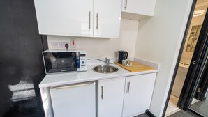 Ett litet, praktiskt kök med mikrovågsugn, kaffebryggare och diskho.
