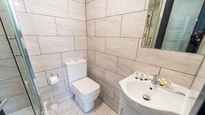 A modern bathroom with a glass shower enclosure, a toilet, and a sink with toiletries. - Modern Studio 10 Mins on Train to City! (Birmingham)