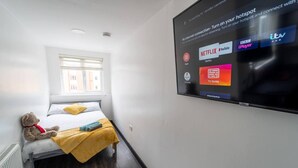 A hotel room with a bed, a teddy bear, and a TV displaying streaming services. - Stunning Studio Next to Restaurants! (Birmingham)