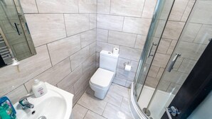 A modern bathroom with a toilet, sink, and glass shower enclosure. - Stunning Studio Next to Restaurants! (Birmingham)