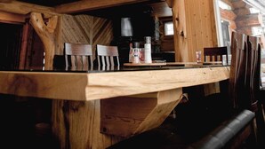Een houten interieur met zichtbare balken, een houten bar en hangende吊り明かり.