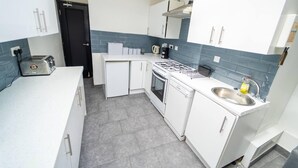 Eine kompakte Küche mit weißen Schränken, einem Gasherd, einer Spüle und einem Toaster.