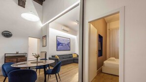 Een moderne woonkamer met een eethoek, een bank, een bed en een groot raam.