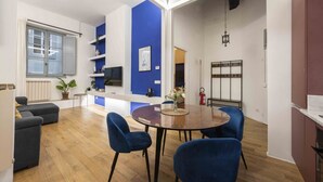 Een moderne woonkamer met een eethoek, een blauwe accentmuur en een groot raam.