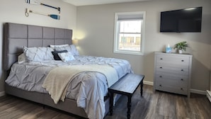 A bedroom with a bed, a nightstand, a dresser, a television, and a window. - Green Lake Condo in the heart of Spicer (Spicer)