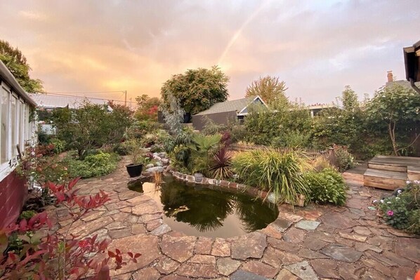 A garden with a pond, stone pathway, and various plants. - Kenton Garden Home: 2 minutes to shops, food & transit (Portland)