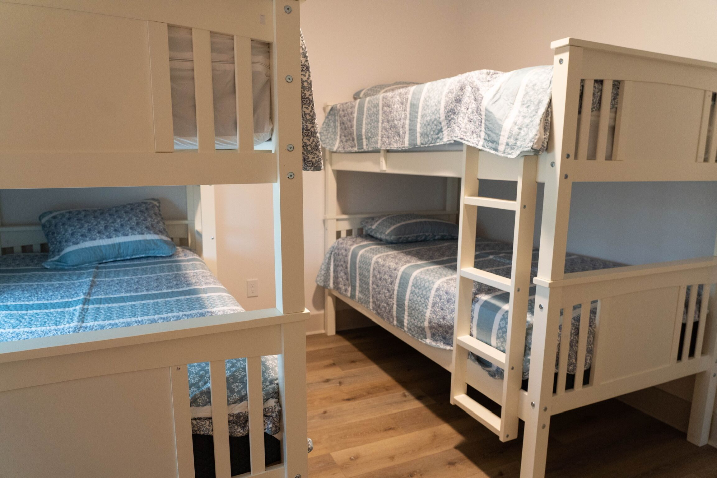 A bunk bed room with two beds, each with a patterned bedspread and pillows.