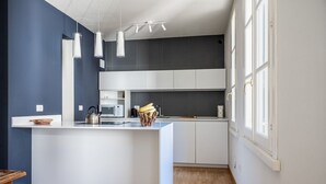 Eine moderne Küche mit Kochinsel, weißen Schränken und Pendelleuchten.
