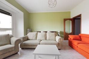 Un salon avec un canapé, une table basse et un divan d’un orange vif.
