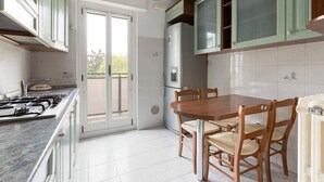 Eine Küche mit Herd, Kühlschrank und Esstisch mit Stühlen.
