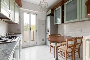 Una cocina con estufa, refrigerador y mesa de comedor con sillas.