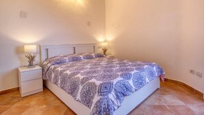 Une chambre à coucher avec un lit, des tables de chevet et des lampes fixées au mur.