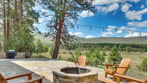 An outdoor patio with a stone fire pit, wooden Adirondack chairs, and a grill. - Peaceful Nutrioso Cabin Retreat w/ Mountain Views! (Nutrioso)