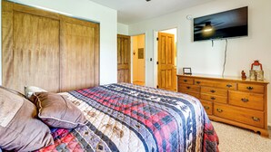 A bedroom with a bed, wooden wardrobe, dresser, and a TV mounted on the wall. - Peaceful Nutrioso Cabin Retreat w/ Mountain Views! (Nutrioso)